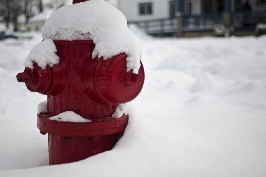 A red fire hydrant covered almost entirely by snow