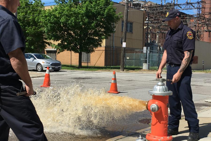 A firefighter opens a hydrant and wash rushes out