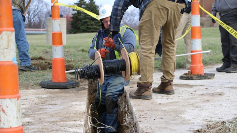 Cleveland Water employees unspool a line of temperature sensors to install in a trench